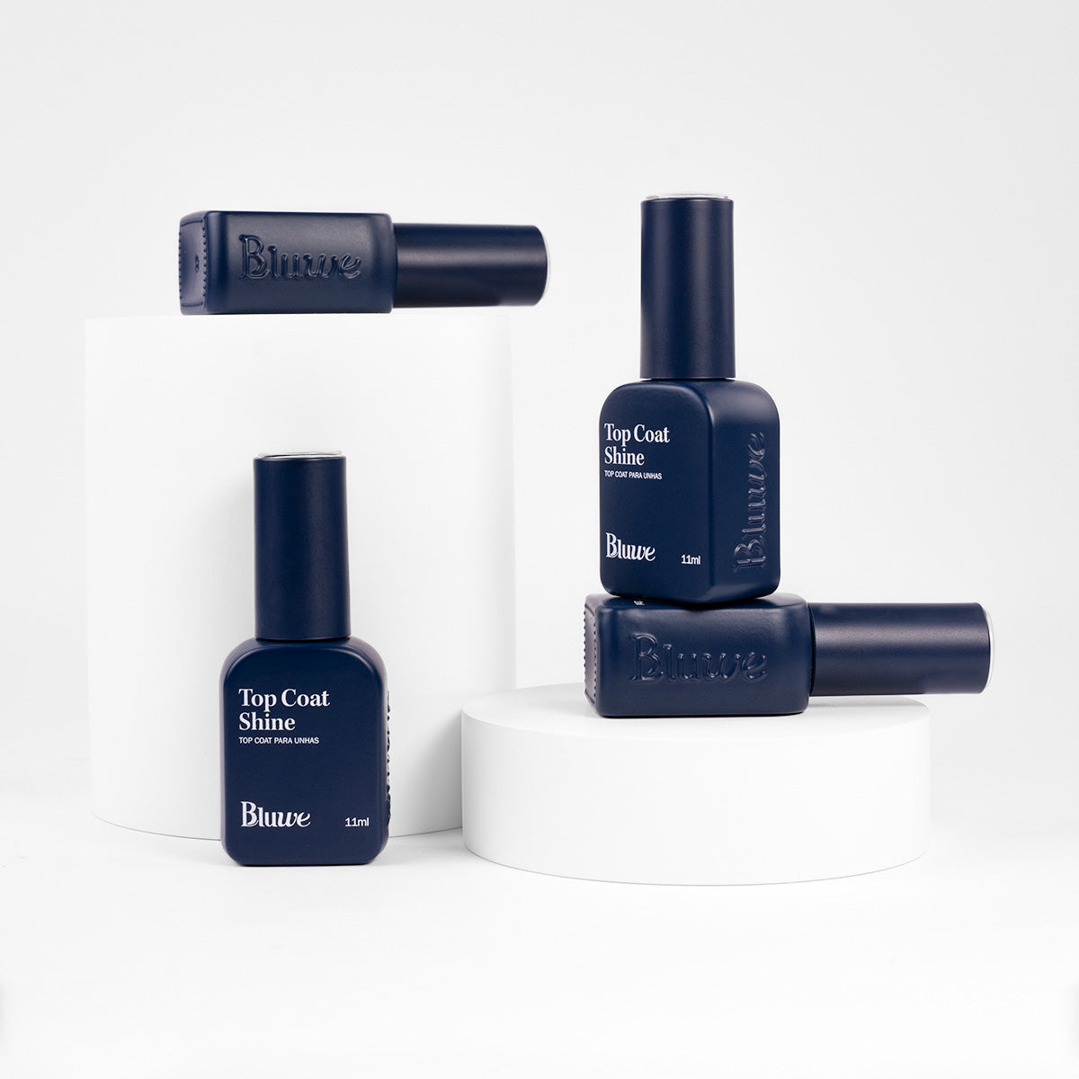 Quatro potes do produto Top Coat Shine da marca Bluwe. Os vidros são no formato de esmaltes