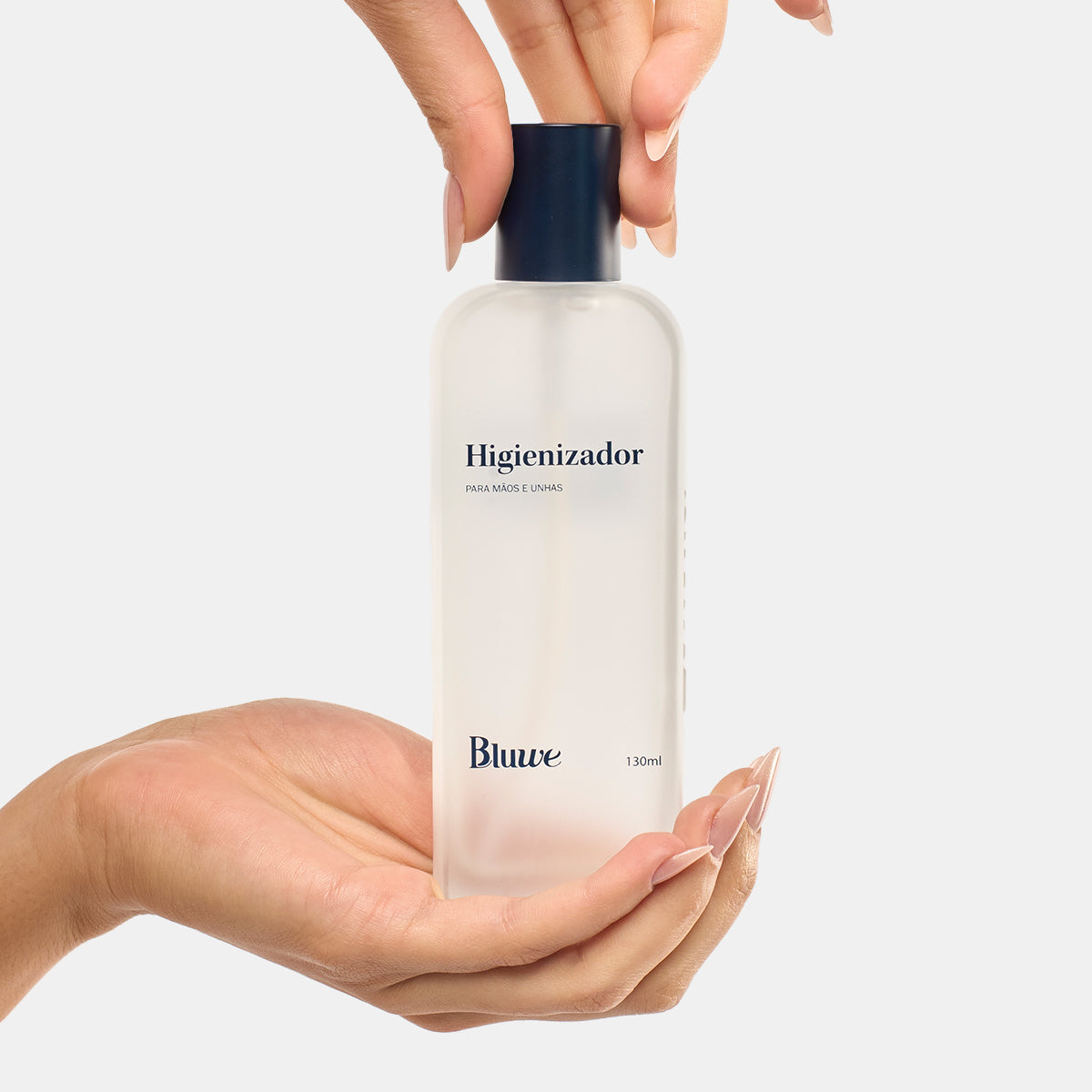Mãos segurando o novo frasco do Higienizador da Bluwe em fundo branco