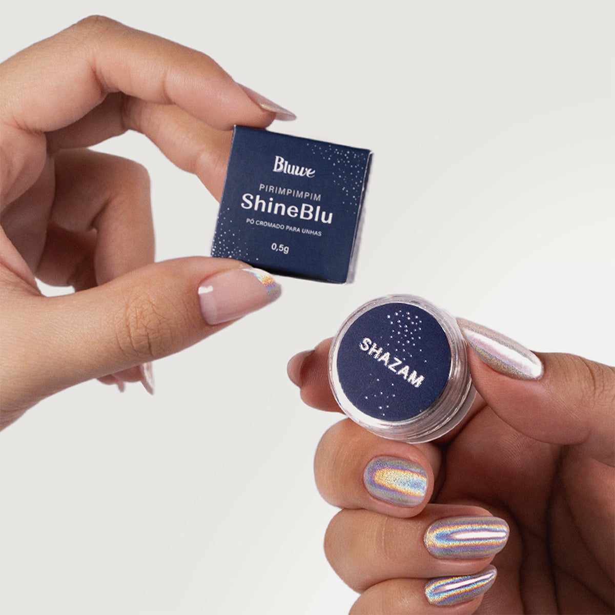 Duas mãos diferentes, uma segurando a caixa do ShineBlu e outra o pote do Pó Cromado Shazam. Cada mão tem uma aplicação diferente
