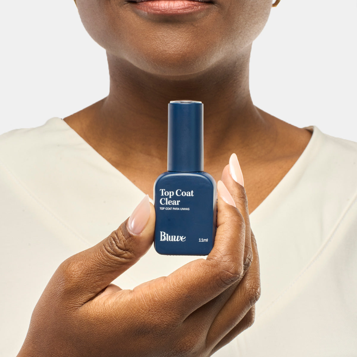 Mulher ao fundo segurando o vidro do produto Top Coat Clear