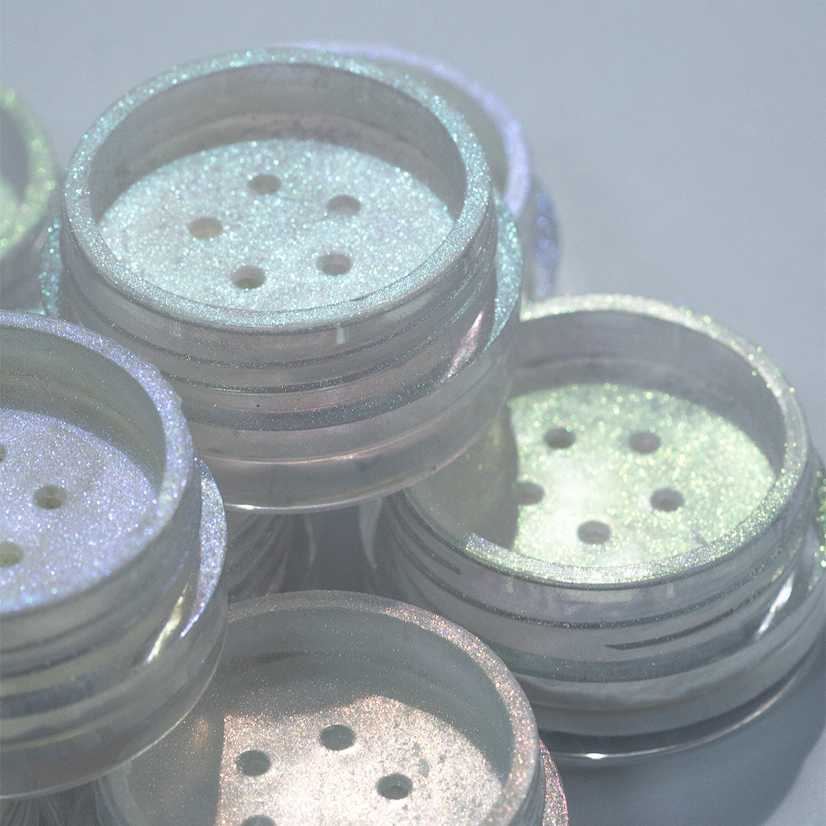 Kit de pós cromados de diversas cores, os produtos são utilizados para fazer unha em gel. A foto contém um filtro de opacidade branca.